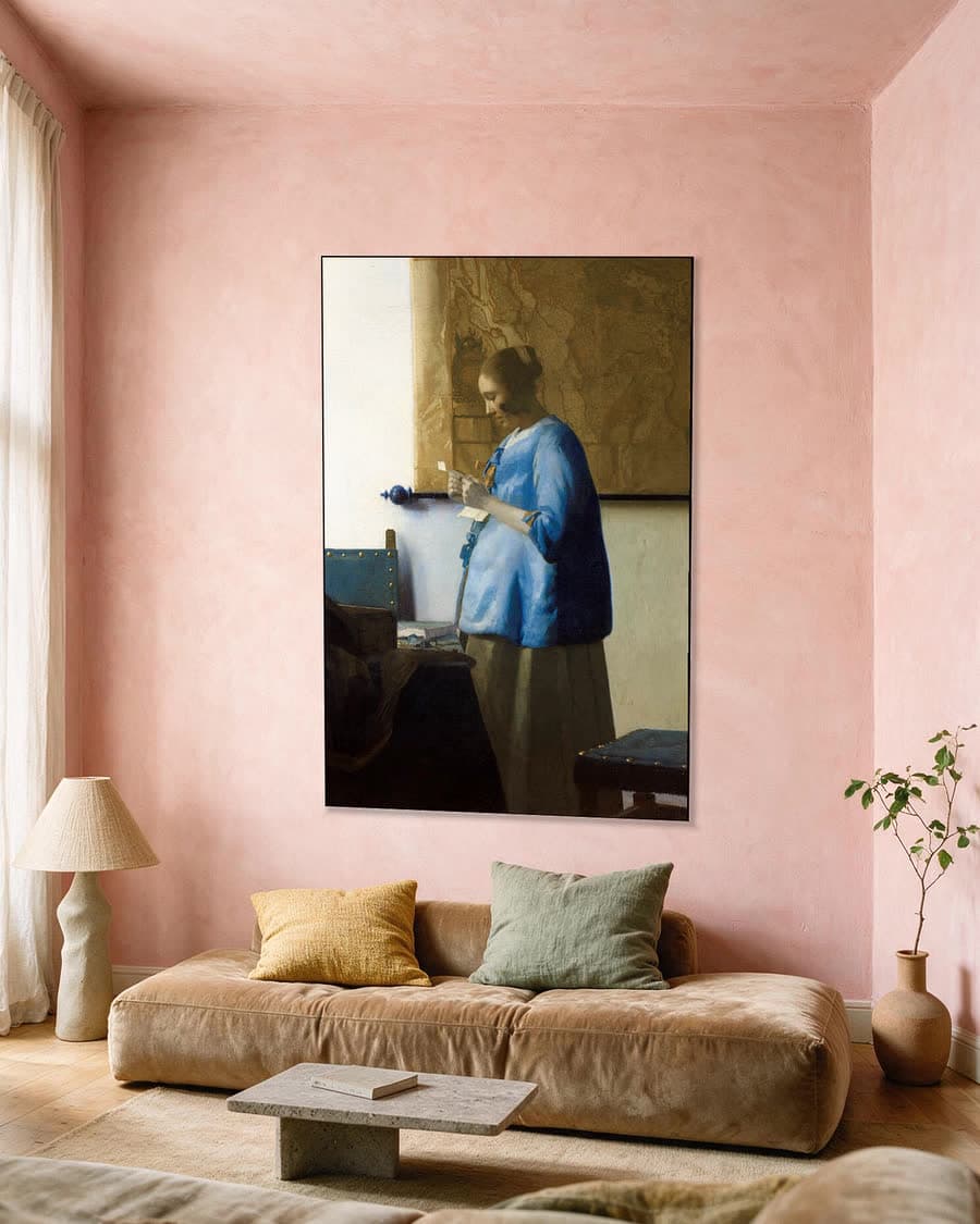 Brieflezende Vrouw in het Blauw in een aluminium frame aan dezelfde muur