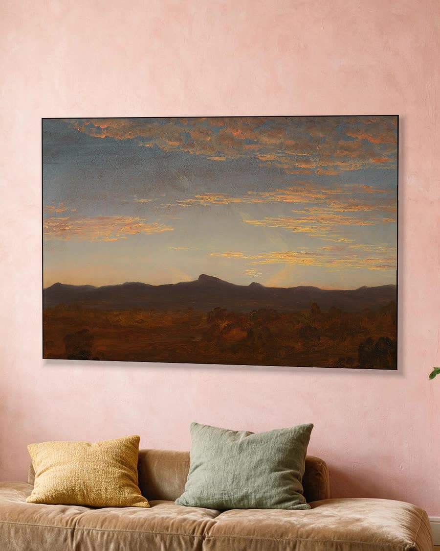 Avondgloed boven de bergen in een aluminium frame aan dezelfde muur