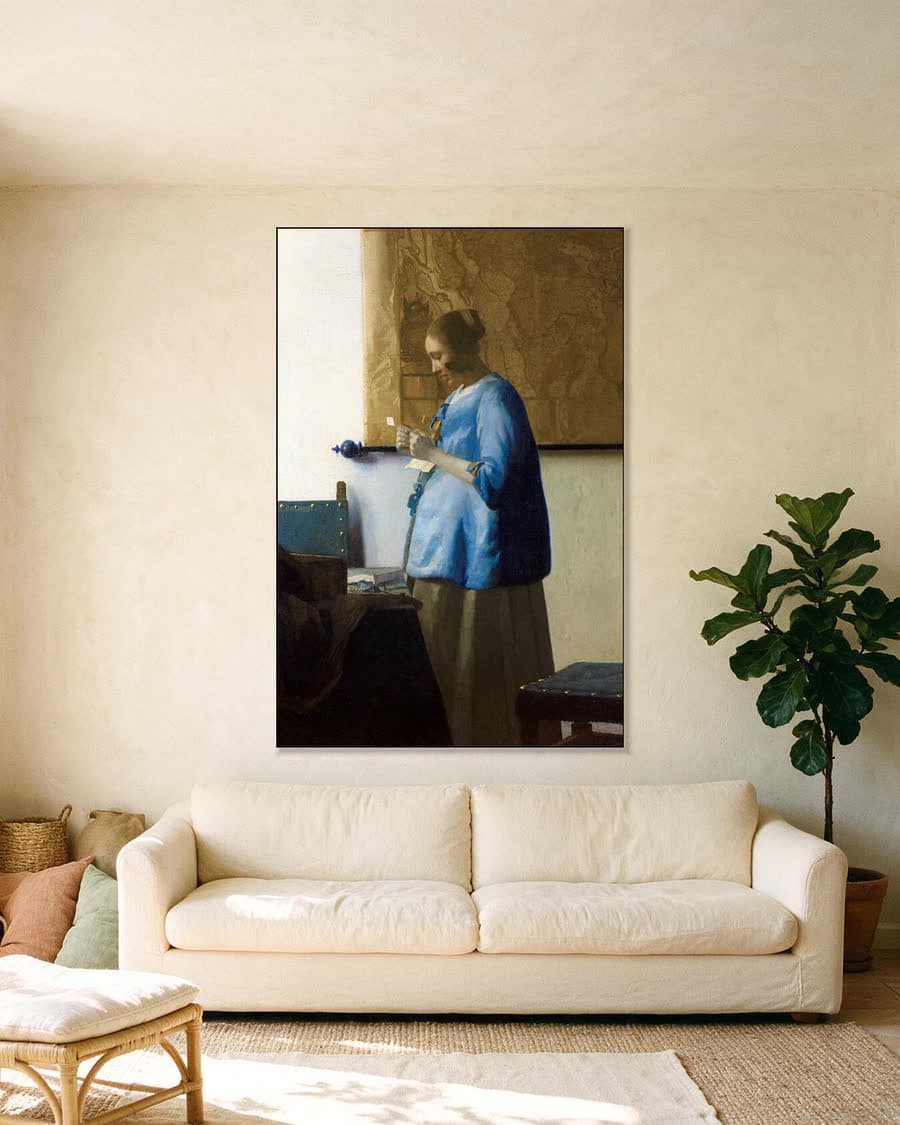 Brieflezende Vrouw in het Blauw in een aluminium frame aan dezelfde muur