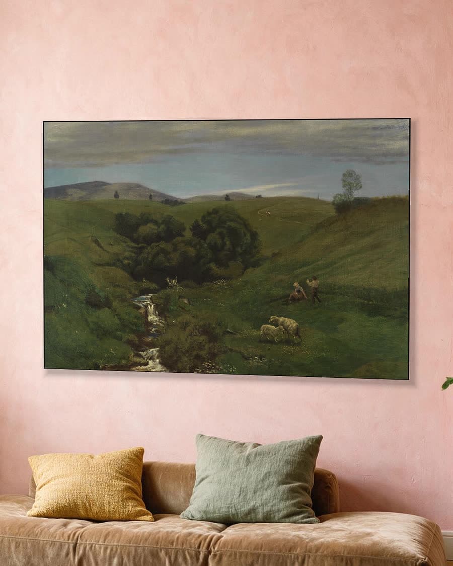 Heuvelachtig landschap met beek en schapen in een aluminium frame aan dezelfde muur