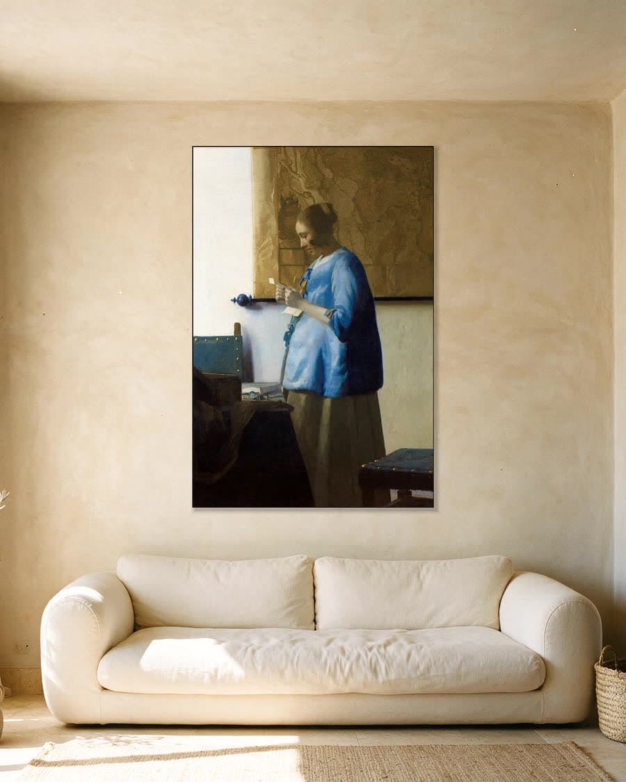 Brieflezende Vrouw in het Blauw in een aluminium frame aan dezelfde muur