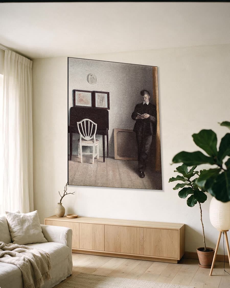 Interieur met een lezende jonge man in een aluminium frame aan dezelfde muur