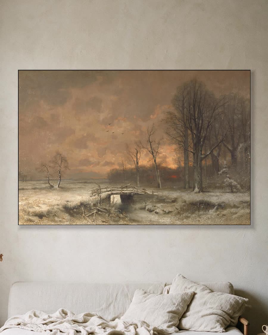 Wintergezicht met ondergaande zon tussen het geboomte in een aluminium frame aan dezelfde muur