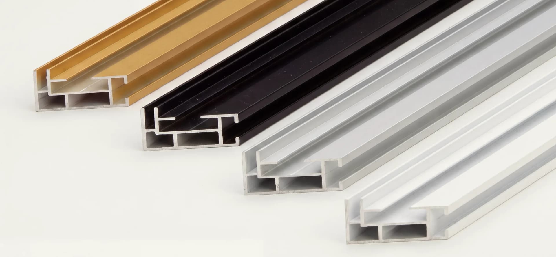 Vier aluminium frameprofielen naast elkaar, van links naar rechts goud, zwart, grijs en wit