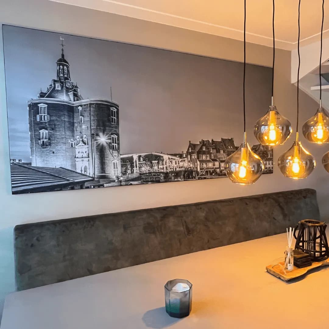 Zwart-wit stadsgezicht van de Drommedaris boven een wandbank met sfeerverlichting
