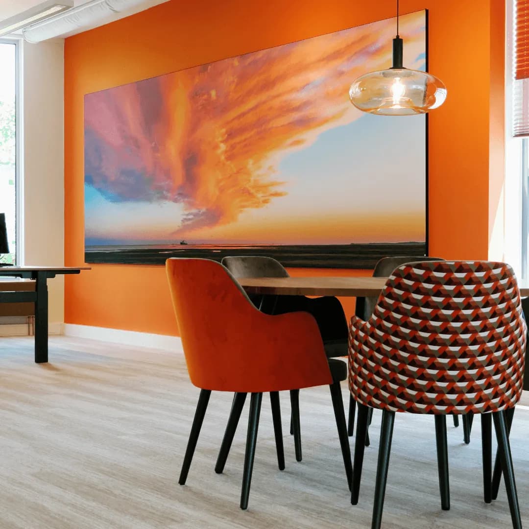 Groot kunstdoek met avondlucht op een oranje kantoorwand, vergadertafel ervoor